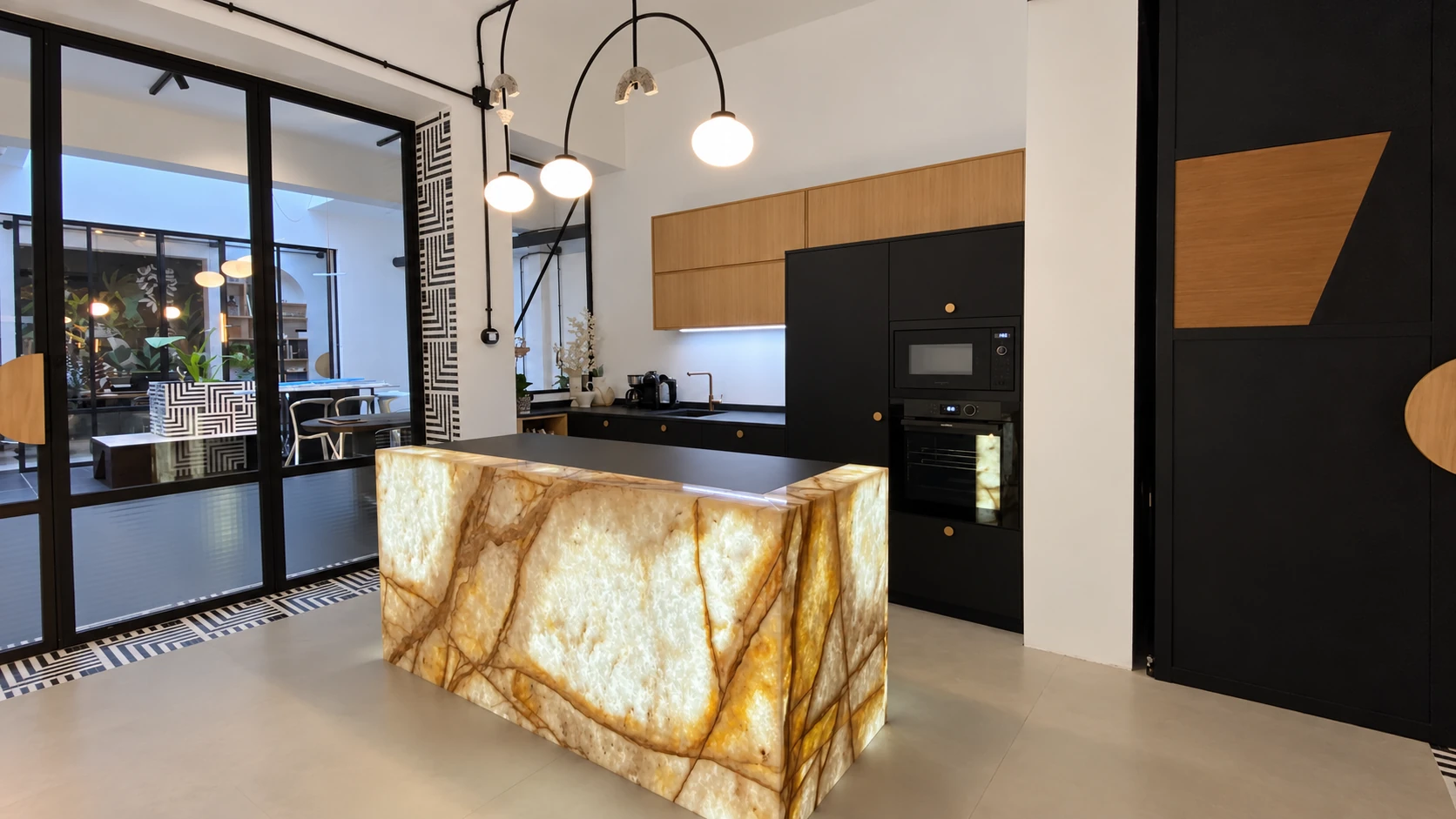 Zona de cocina con isla de piedra retroiluminada y cerramiento de cristal en el local de calle Arquitectura.