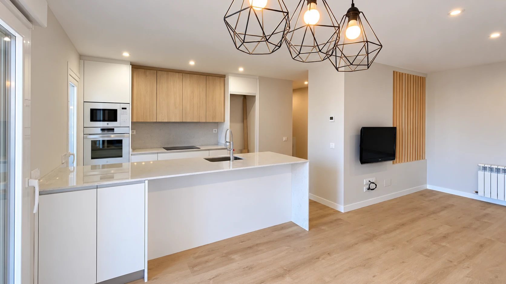 Cocina abierta con península blanca, muebles de madera y lámparas geométricas en Motilla del Palancar.