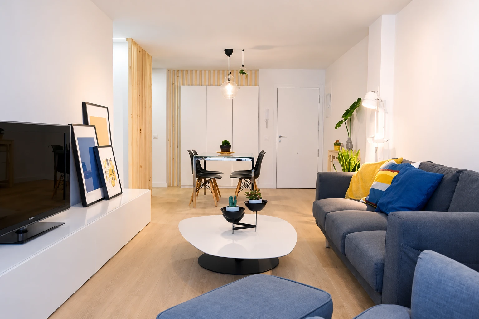 Salón comedor con sofá azul y detalles de madera en la vivienda de Parla.