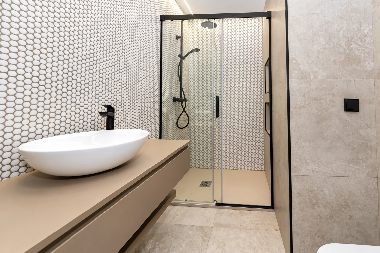 Baño con lavabo sobre encimera y ducha de perfilería negra en la vivienda de calle Tarragona.